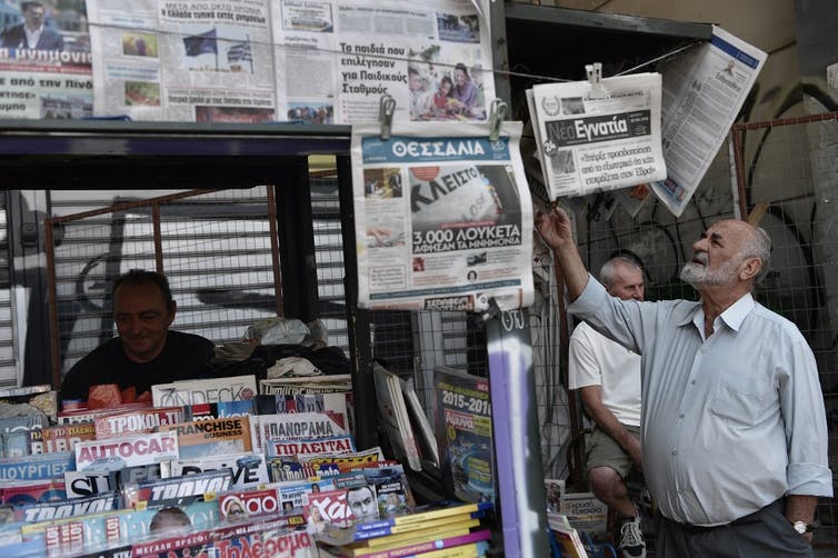 Un homme regarde les journaux annonçant la fin du cycle de dettes à Athènes le 21 août 2018.